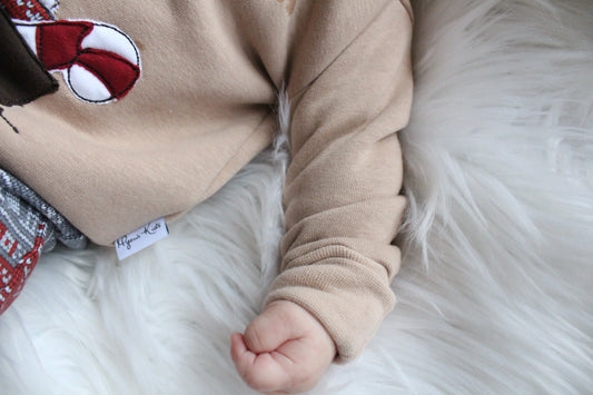 Weihnachtsoutfit für Babys und Kleinkinder. Das Set besteht aus einem oversized geschnittenen Sweater mit wunderschöner Applikation und einer weihnachtlichen Hose.